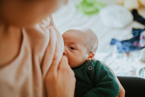 A closeup image of a newborn baby nursing from a woman's breast