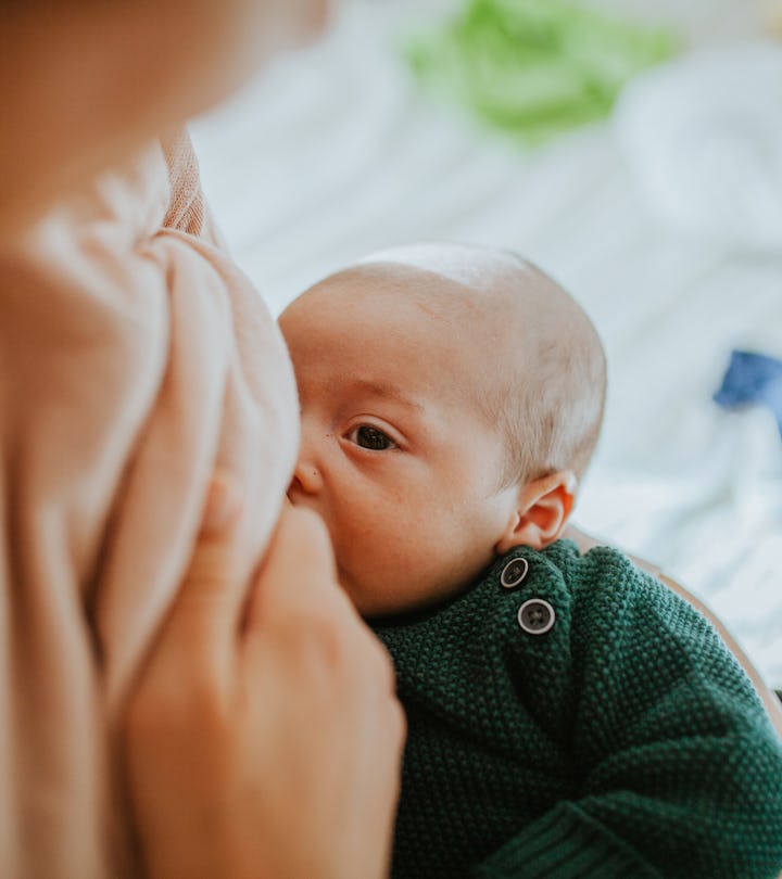 A closeup image of a newborn baby nursing from a woman's breast