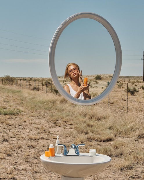 Woman in desert with mirror and skin care products