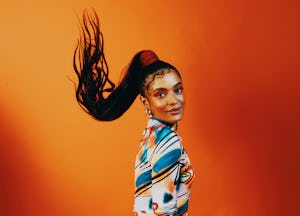 A young Black woman flips her long ponytail and killer makeup, looking ready to go back to school wi...