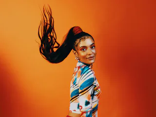 A young Black woman flips her long ponytail and killer makeup, looking ready to go back to school wi...