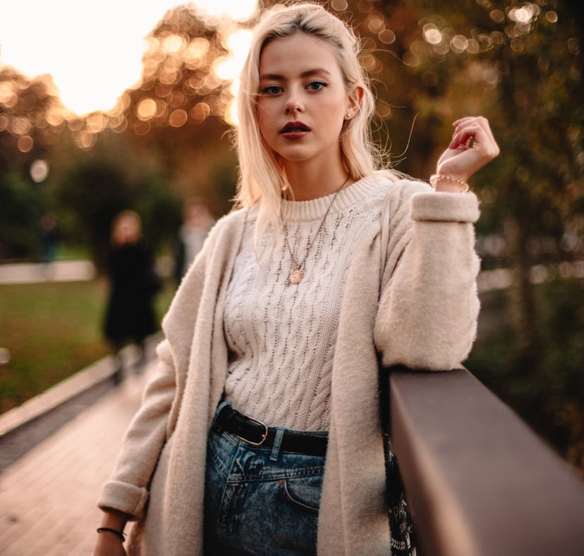 Young woman in a cableknit sweater during the 2021 fall equinox, which will affect her zodiac sign m...