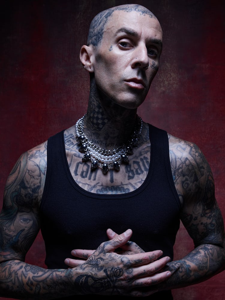 NYLON cover star Travis Barker poses with his hands against his chest.