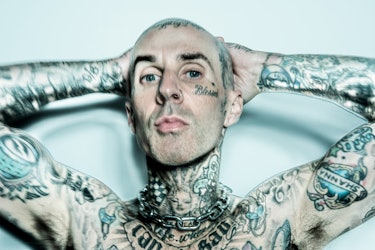 A close-up image of Travis Barker with his hands behind his head, shot in color.