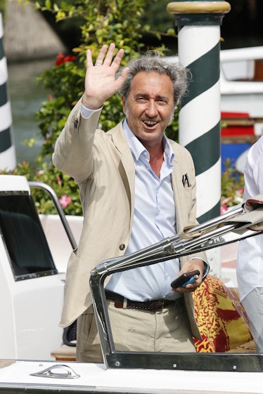 Paolo Sorrentino in a tan suit waving