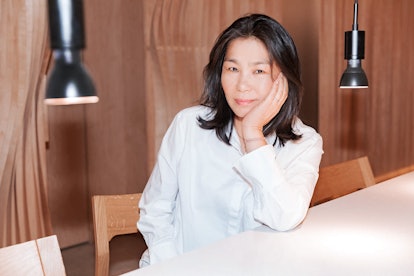 Jin Soon Choi in a white shirt, sitting next to a table while leaning her elbow on the table