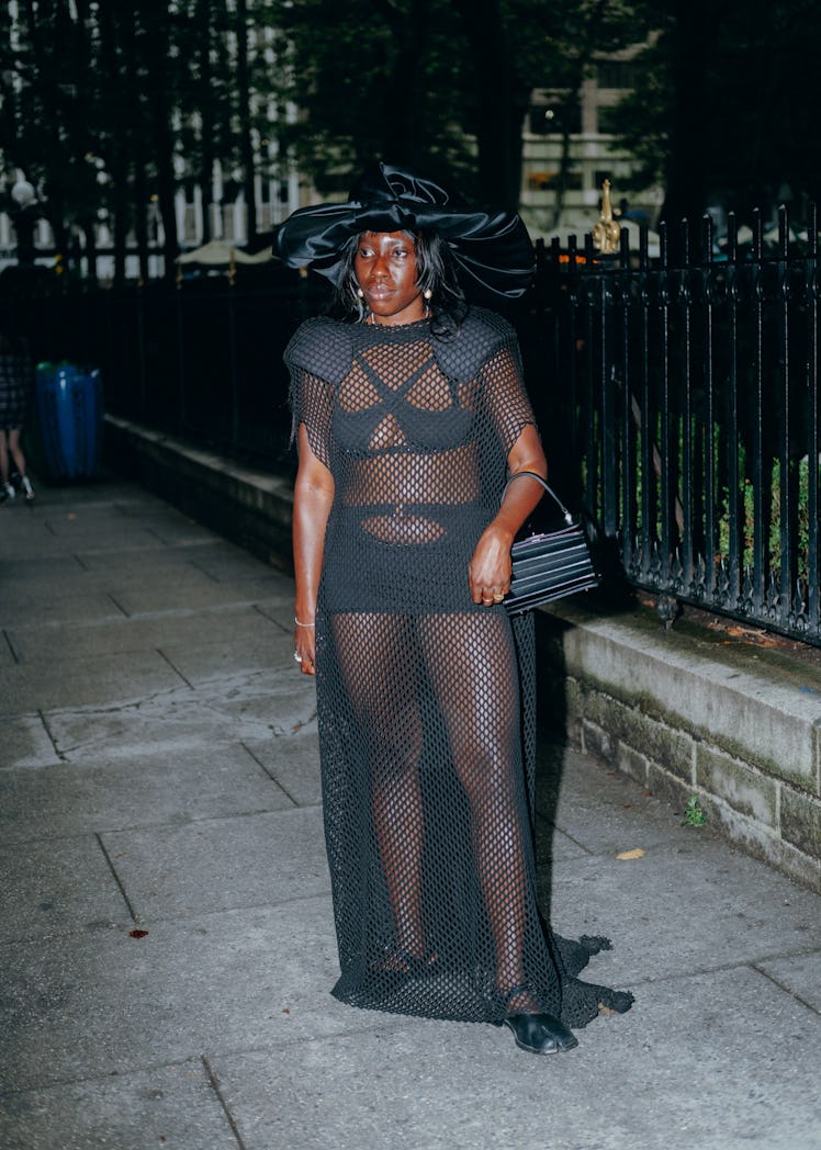 Woman wears a mesh dress with a large hat.
