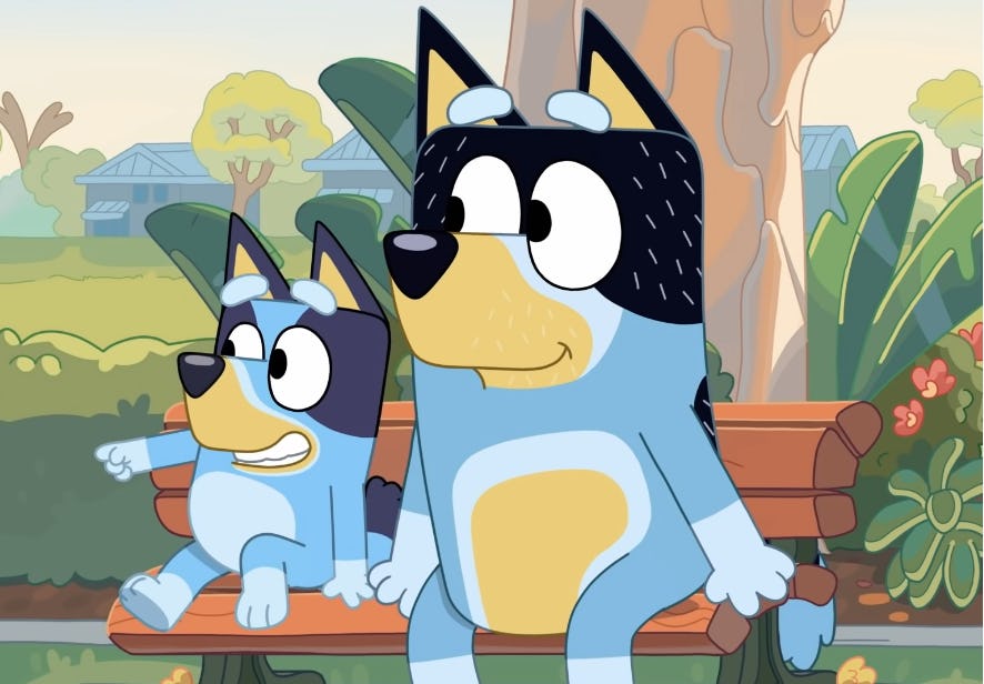 Bluey and her dad Bandit sit on a bench at the playground.