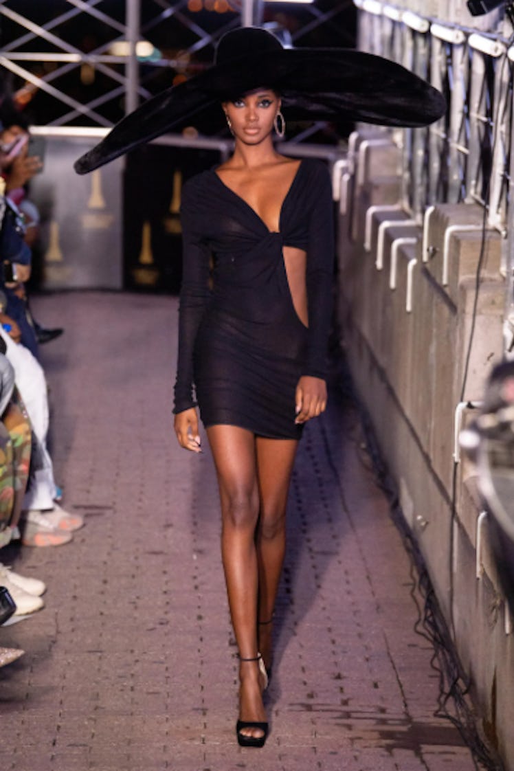 A model walking the runway in a black cut-out dress and a dramatic hat by LaQuan Smith during the NY...