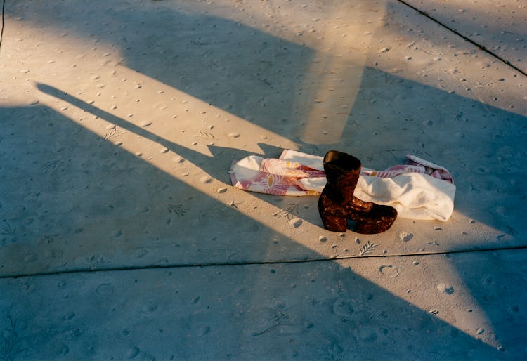 A Prada boot next to a white scarf on a concrete floor