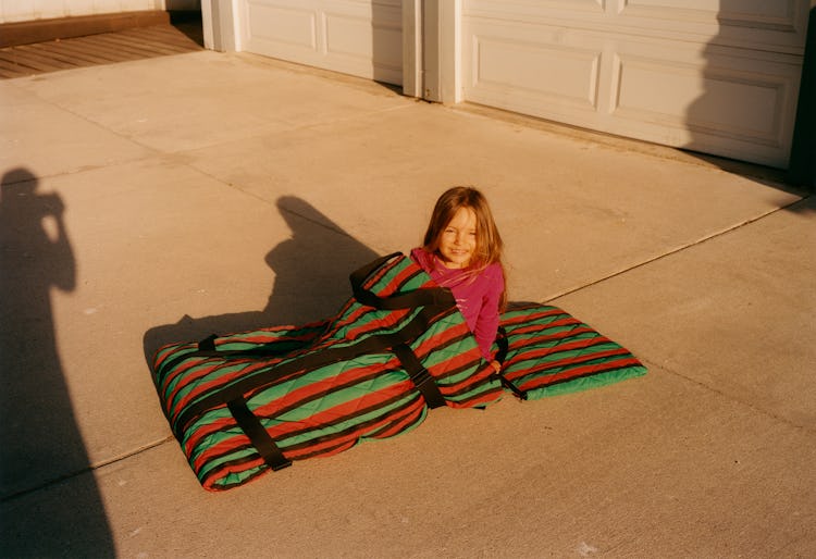 A girl lying in a red-black-green Kenzo sleeping bag.