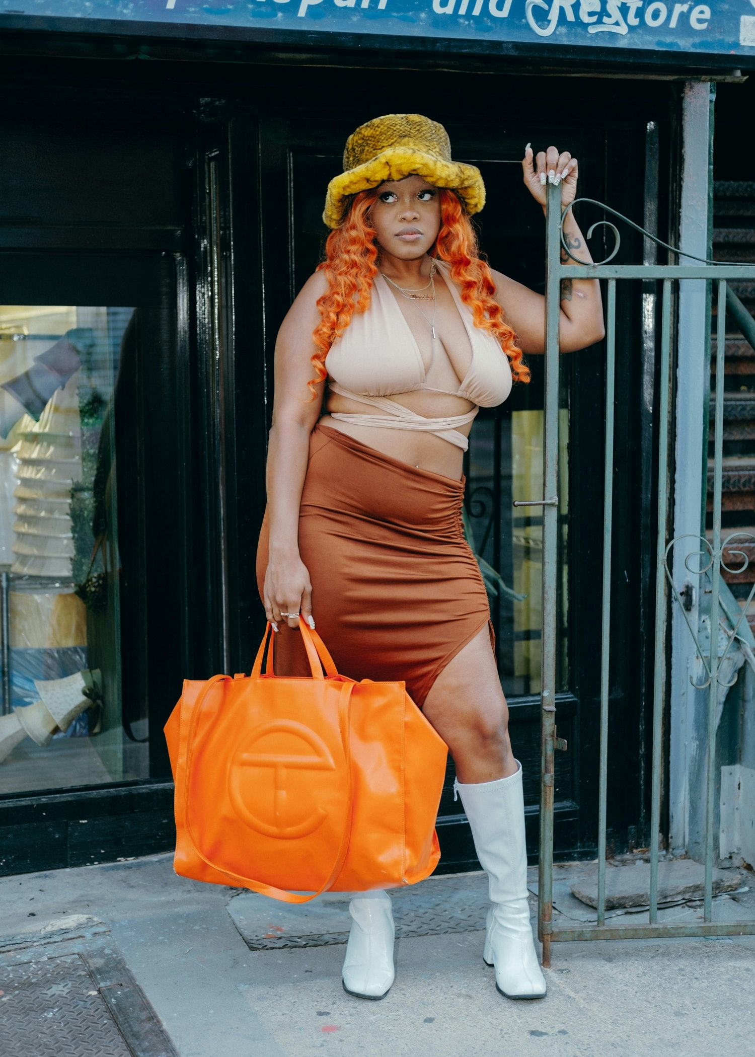 A person carrying an orange Telfar bag