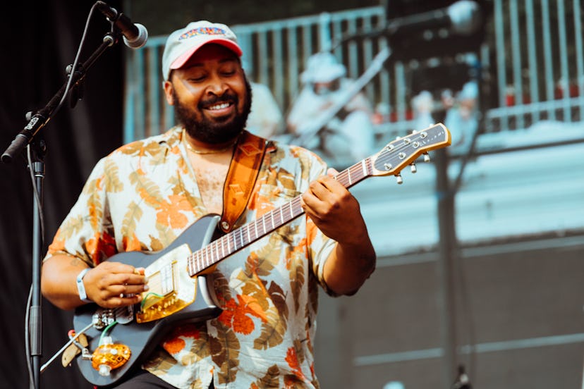 Jackie Lee Young in a baseball hat and patterned shirt playing his guitar at the pitchfork music fes...