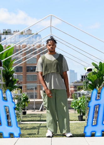 A model in a piece from Tombogo's "Nature Is Healing": gray oversized tee, green cropped vest and gr...