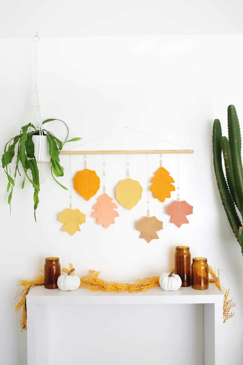 Felt leaves in orange pink and yellow hanging from wooden dowel 