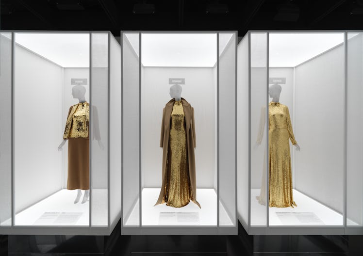 Three gold sequinned outfits in museum display cases. 