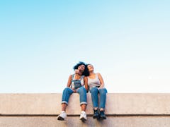 A pair of best friends — a Libra and her sister sign, Aries — sitting on a wall.