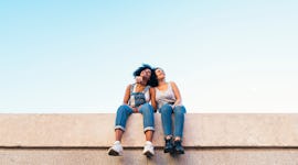 A pair of best friends — a Libra and her sister sign, Aries — sitting on a wall.