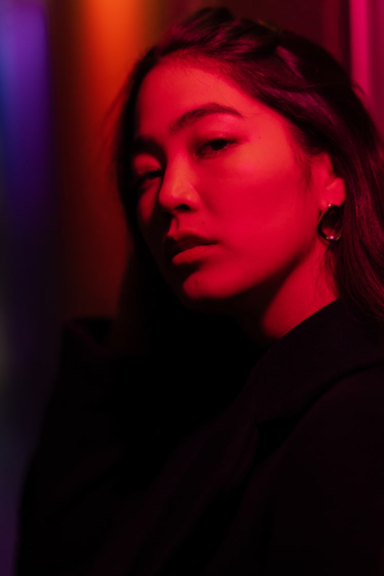 Young woman in red neon lighting, writing a spell to manifest what she wants out of life.
