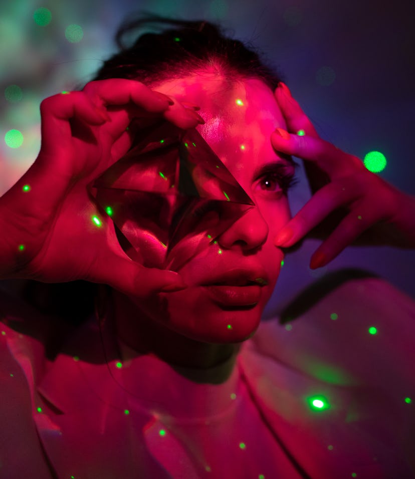 Young woman looking through a crystal to show what a vertex is in astrology.
