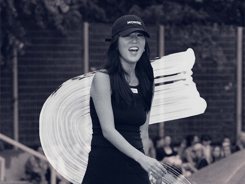 Laura Kim walking in a black dress a cap and high heel shoes