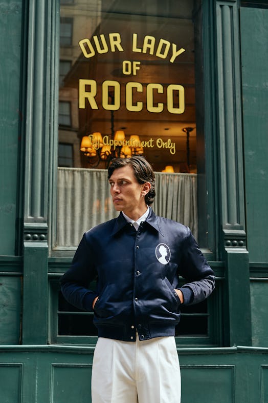 model standing in front of restaurant with blue jacket and white pants
