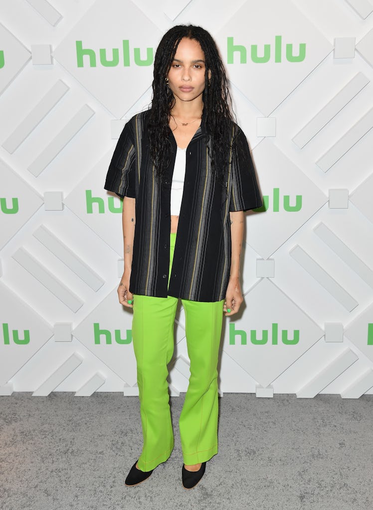 Zoe Kravitz at a Hulu event in green pants, a black short-sleeved button-up and a white tank top und...