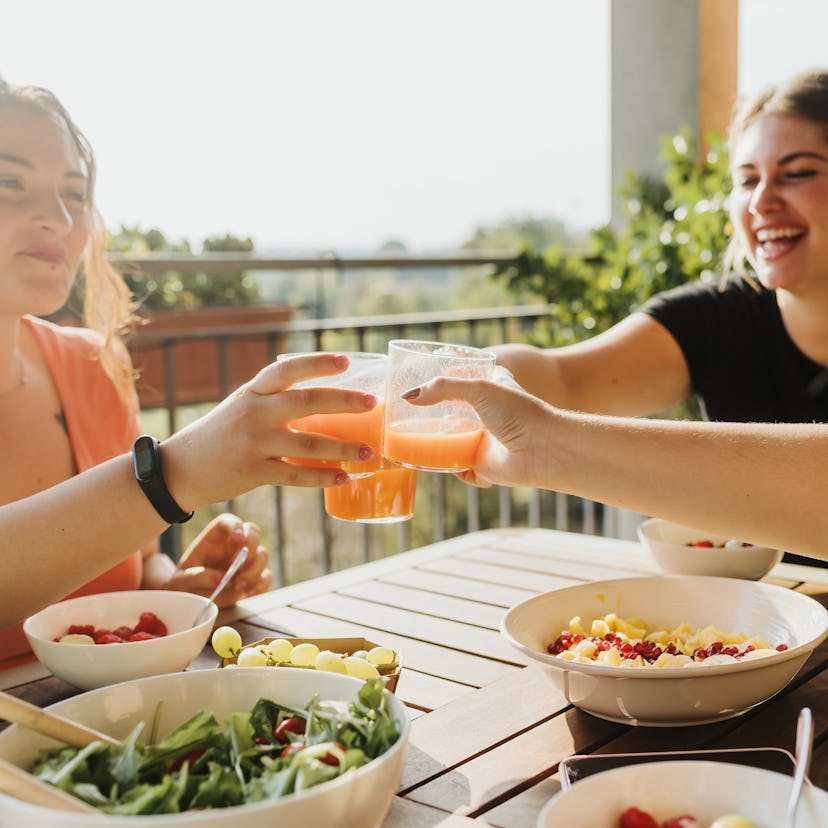 Friends cheersing, clinking glasses to show each zodiac sign has a drink that goes with it.