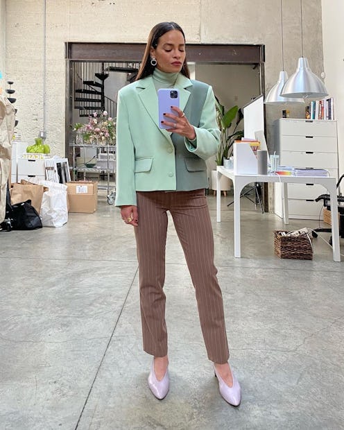 stylist Sophie Lopez standing in her studio wearing a dual green blazer, brown pants and pink pumps