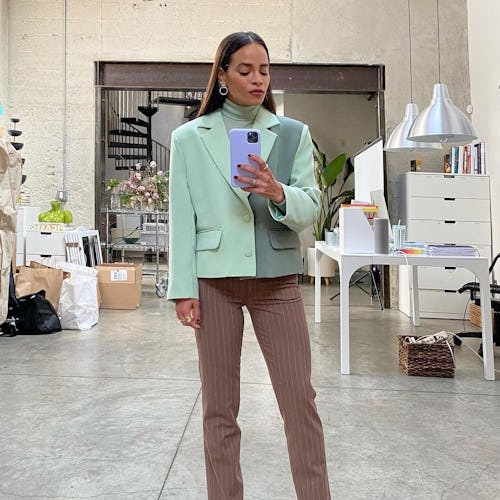 stylist Sophie Lopez standing in her studio wearing a dual green blazer, brown pants and pink pumps