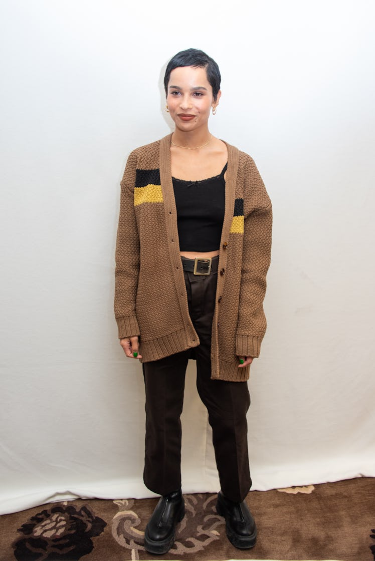 Zoe Kravitz in a brown cardigan, black cropped tank top and black jeans 
