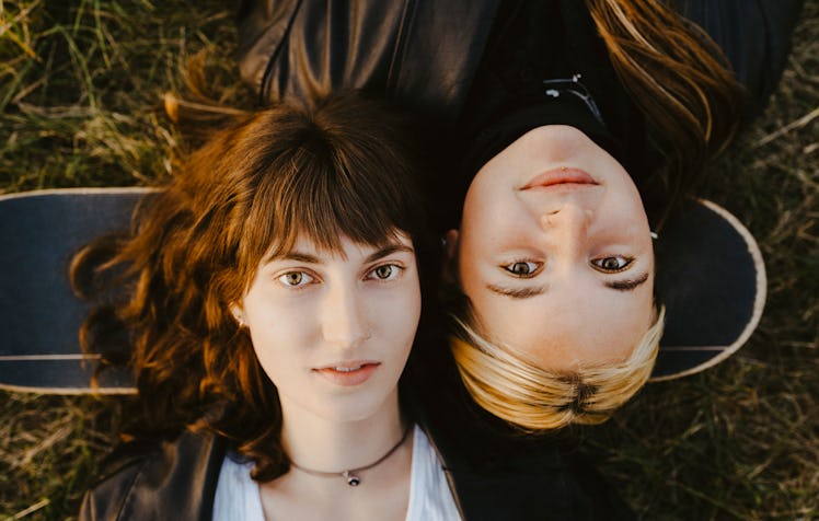 2 young women laying in grass during the 2021 fall equinox, which has a special emotional meaning.