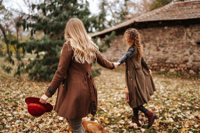 Young couple holding hands while walking through leaves in fall 2021, the most romantic season for t...