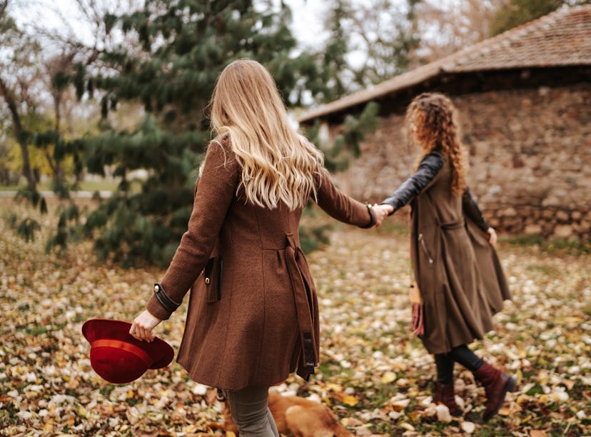 Young couple holding hands while walking through leaves in fall 2021, the most romantic season for t...