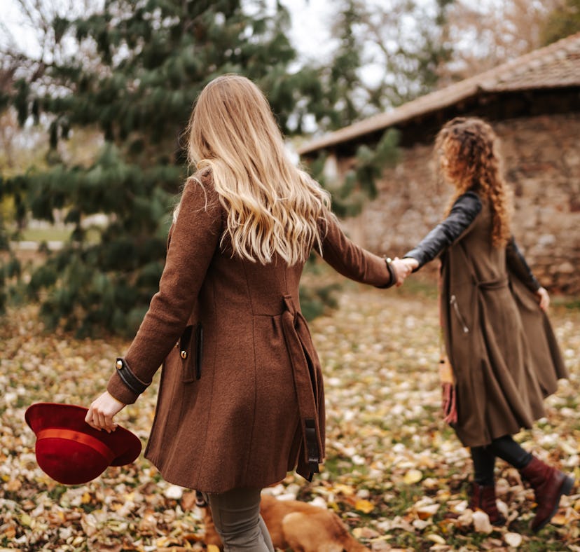 Young couple holding hands while walking through leaves in fall 2021, the most romantic season for t...