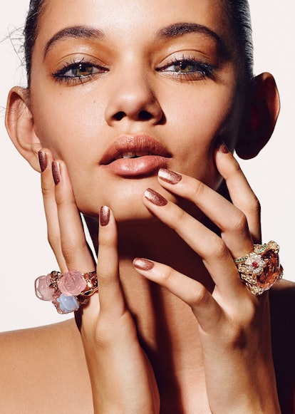 Model with cared face skin posing with hands on her face and gold rose rings on fingers