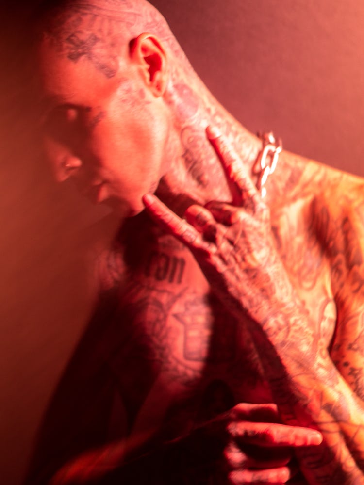 A side-profile image of Travis Barker in front of a red backdrop.