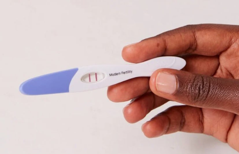 Hand holding a positive pregnancy test