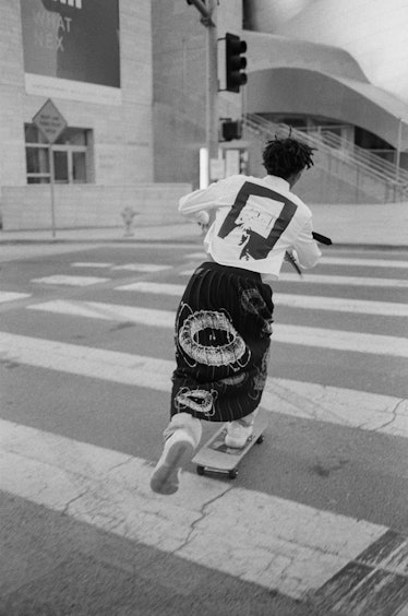 While sporting his own brand MSFTS, Jaden Smith rides a skateboard.