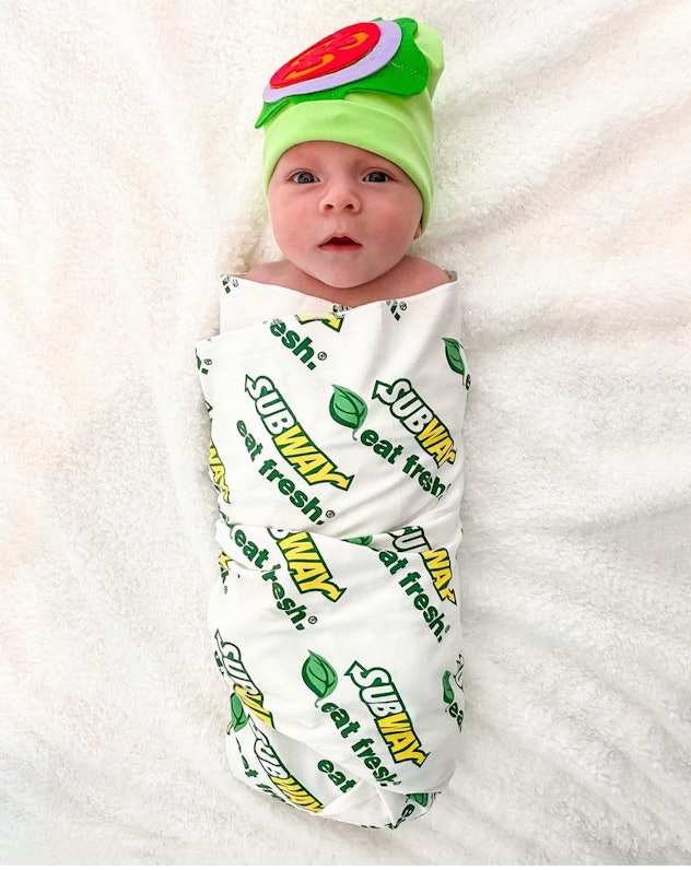 small baby wearing a subway sandwich costume with a printed blanket and tomato and lettuce hat