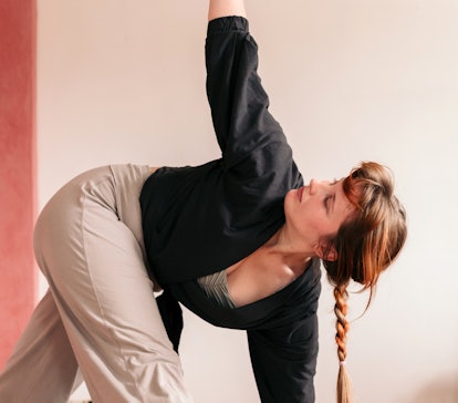 Young woman doing an easy yoga move in her dorm room.