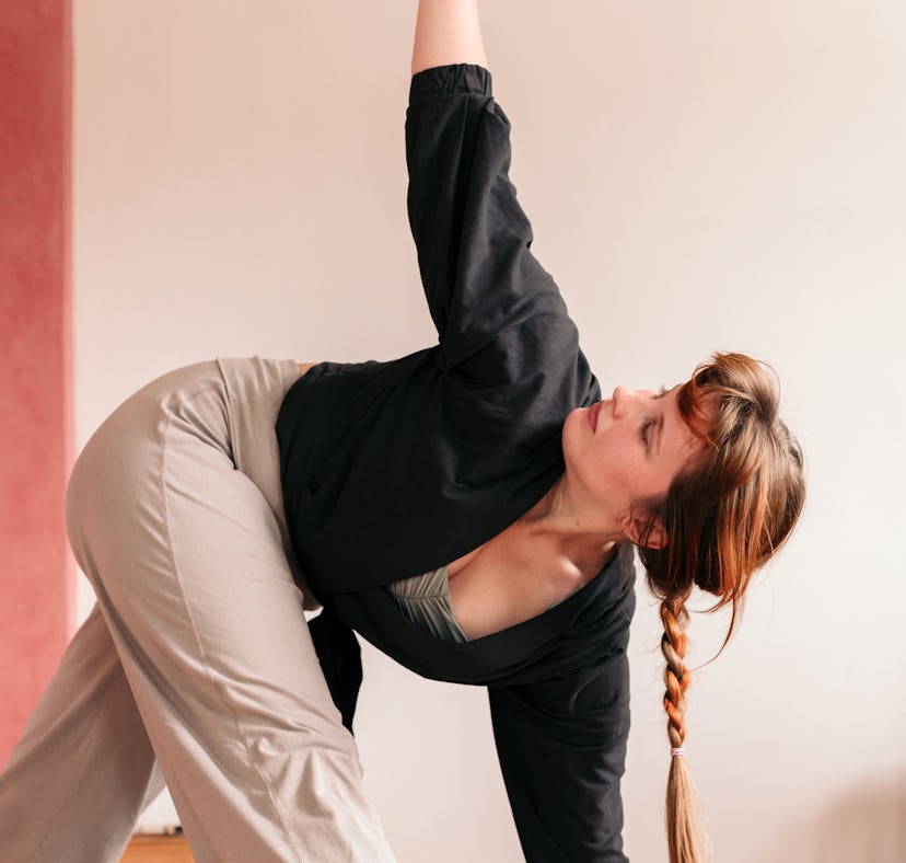 Young woman doing an easy yoga move in her dorm room.