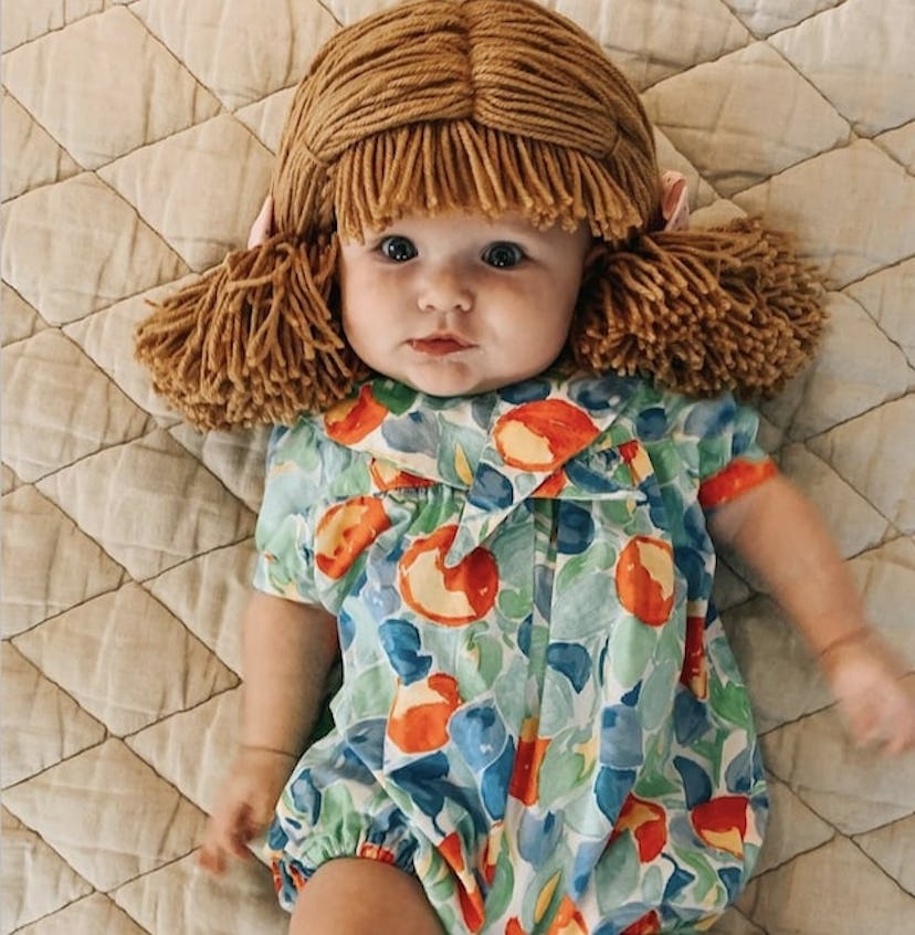 baby dressed as Cabbage Patch doll for Halloween, wearing romper and string wig