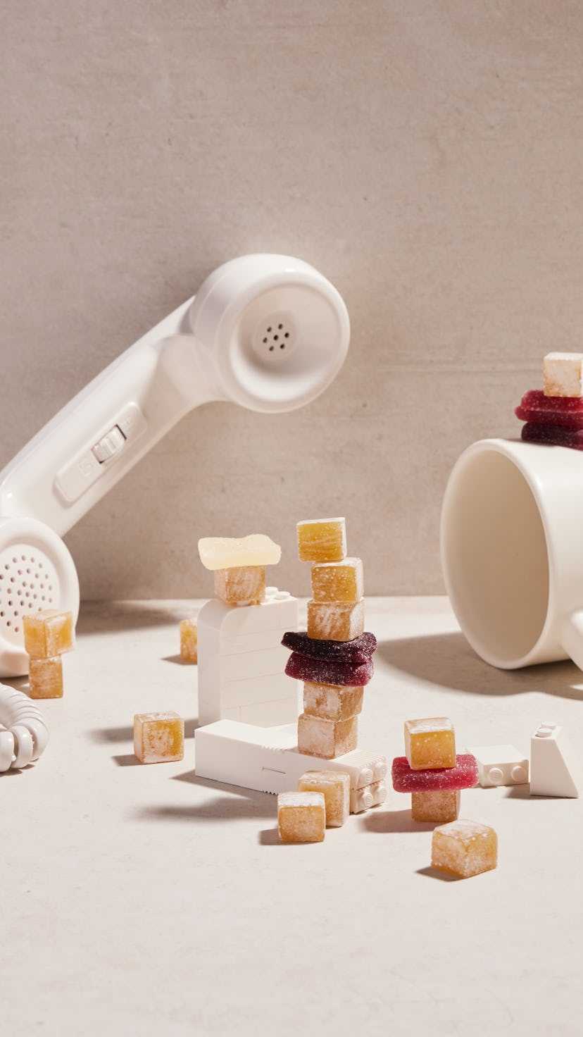 artfully arranged CBD gummies, with a phone, a cup, and white legos 