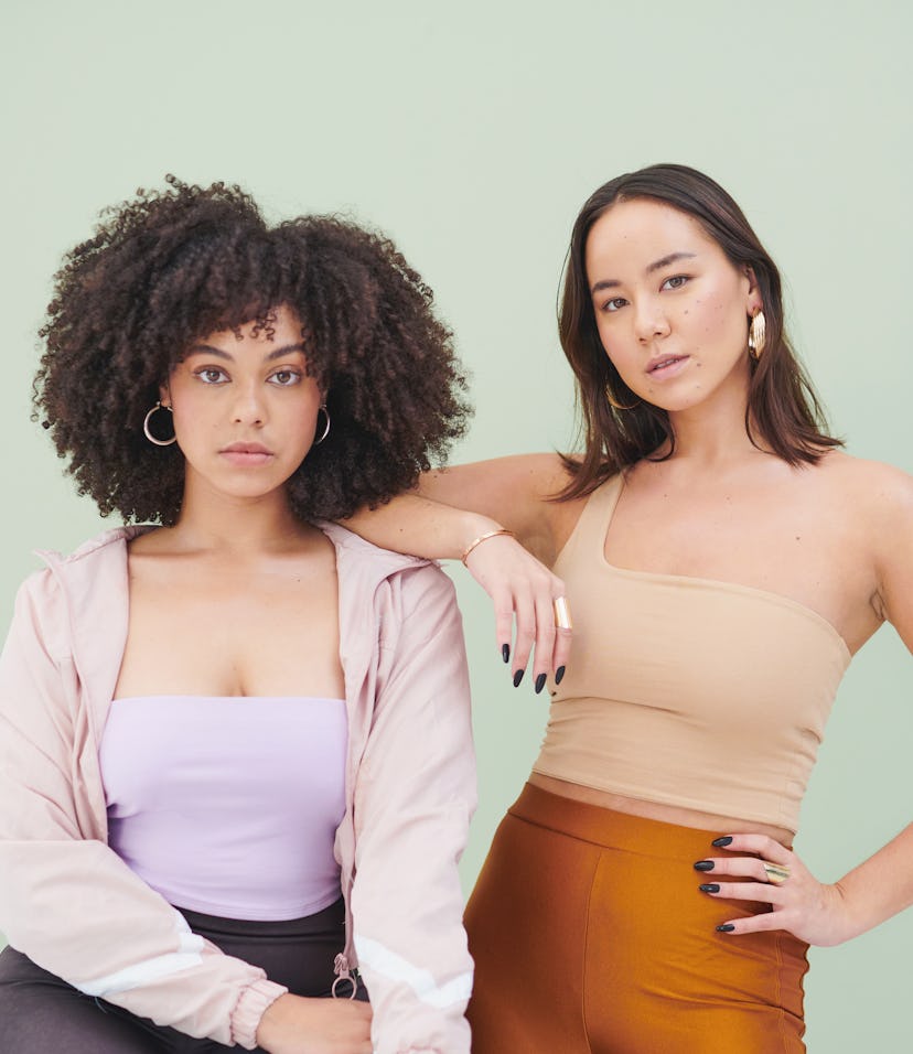 2 women posing against a green background to show the unconventional friendship between a Libra and ...