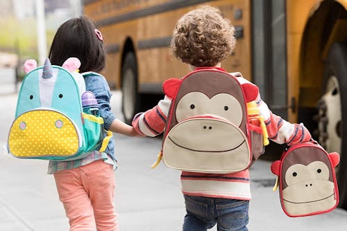 Two preschoolers with a unicorn backpack and a monkey backpack with a matching lunchbox
