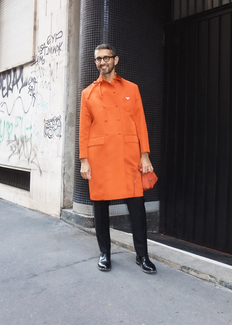 A man in an orange coat and black trousers at Milan Fashion Week 2022