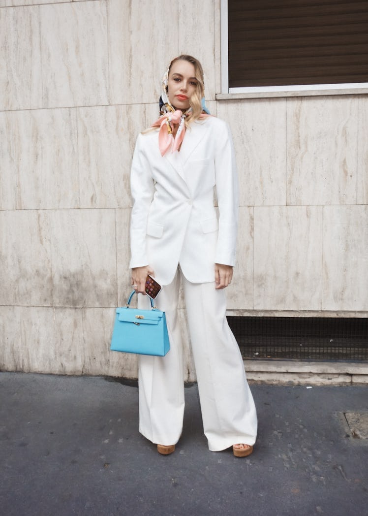 A woman in a white suit and a pastel peach-blue headscarf at Milan Fashion Week 2022
