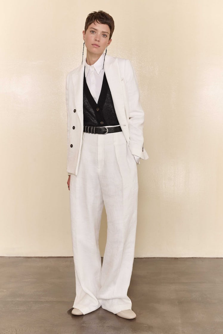A model in a white Brunello Cucinelli suit with a black vest and white button-up underneath 