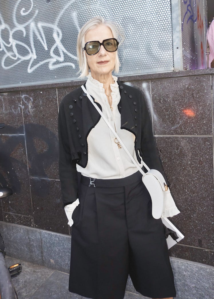 A woman in a beige blouse, black crop jacket and black trousers at Milan Fashion Week 2022